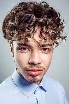 Portrait of young man with curly hairstyle. studio shot. looking at camera and smiling.