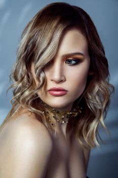 Beauty portrait of beautiful fashion model with makeup, colored wavy hairstyle and accessories on her neck. studio shot on blue background. .