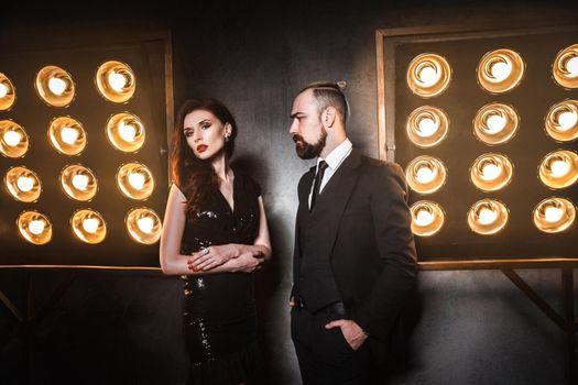 Two beautiful friends wearing elegance, standing near stage. Studio shot