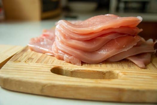 Sliced raw pork loin lying on a wooden board, close-up