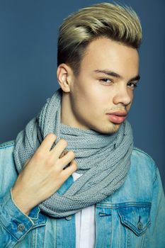 portrait of multiracial handsome man wearing jeans jacket and white shirt on blue wall background.