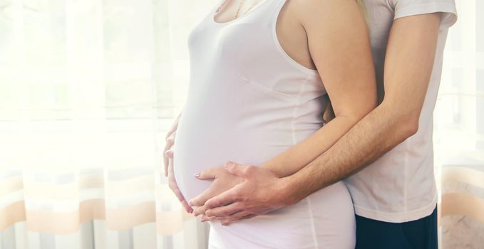 A pregnant woman and a father of a child hug a belly. Selective focus. NATURE.