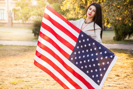 Beautiful happy woman with American flag celebrating independence day.