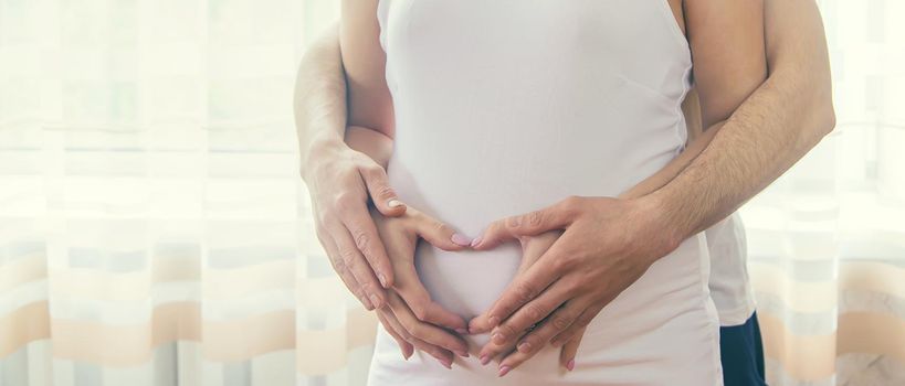 A pregnant woman and a father of a child hug a belly. Selective focus. NATURE.