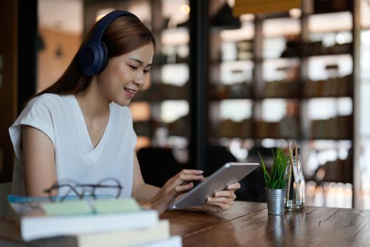 Smiling asian teenage wearing headset looking at tablet listen and learning online courses. Happy chinese business woman with headphones video call. online education concept