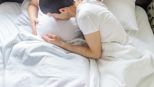 Pregnant woman with man hug belly in bed. Selective focus. people.