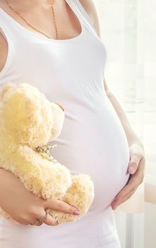 A pregnant woman with a toy hugs her stomach. Selective focus. People.