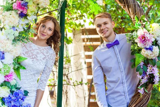 Couple posing in an arch of flowers. Outdoor shot, spring park or summer concept. Love, sensual people