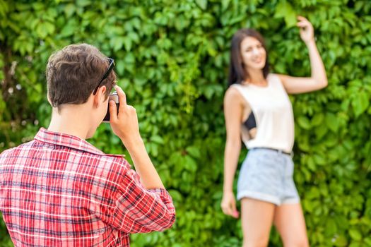 Photographer shooting beautiful brunette model near green wall. .