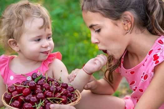 The child eats cherries in the garden. Selective focus. Food.