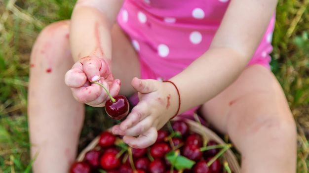 The child eats cherries in the garden. Selective focus. Food.
