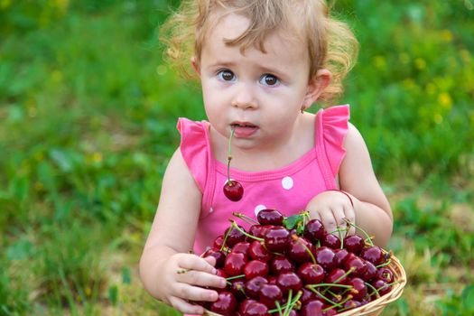 The child eats cherries in the garden. Selective focus. Food.