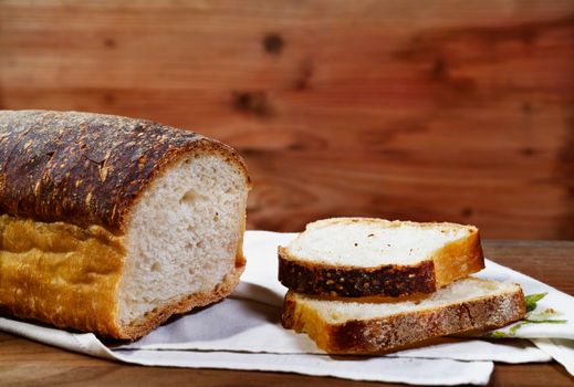 Loaf of bread with sliced bread on white cloth ,