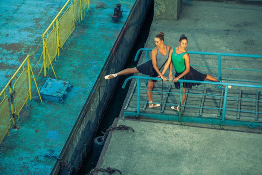 Two young beautiful twin sister dancing ballet in the city with ballet costume. urban sync dance. industrial street dancing. with special effect. synced posing. pointe ballet shoes and dress.