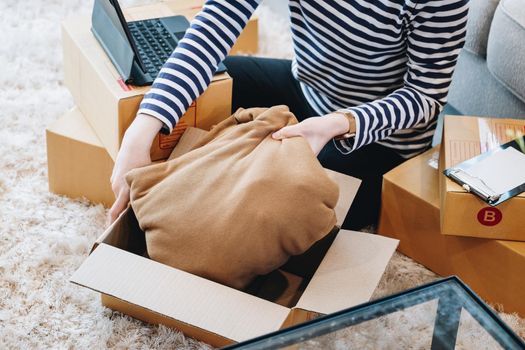 Online merchandising business idea, a beautiful girl is packing pillows in a shipping box to prepare to send items to customers according to orders received from customers