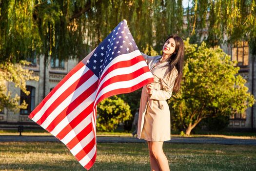 Beautiful happy woman with American flag celebrating independence day.