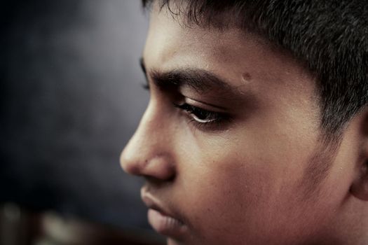 sad teenage boy looking away in dark .