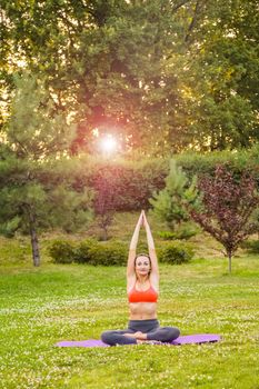 Cheerful young beautiful woman practicing and posing yoga in the park. baddha konasana pose.