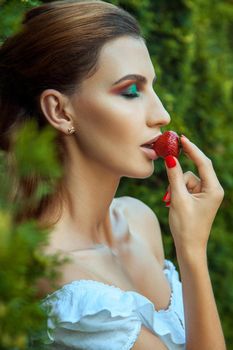 Young adult woman closed eyes and eating red sweet strawberry. Outdoor spring or summer photo