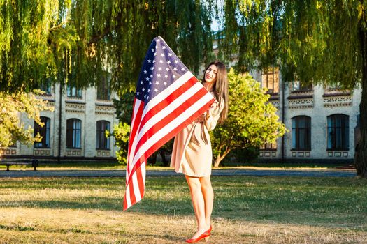 Beautiful happy woman with American flag celebrating independence day.