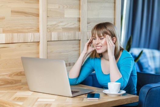 Be waiting an idea! Side view portrait of thoughtful attractive young girl freelancer in blue t-shirt are sitting in cafe and working on laptop, closed eyes and try to remember information. indoor