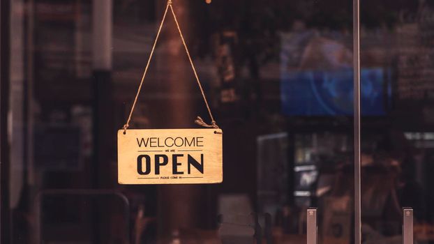 Wooden sign board hanging on door of cafe restaurant .Open vintage sign broad through the glass of store window.commercial business background for advertisement