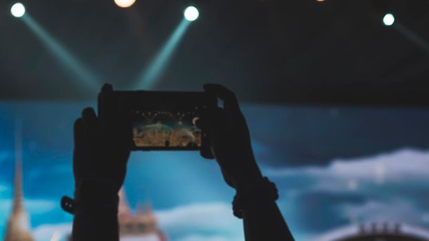 People holding their smart phones and photographing concert . Capture video at a concert at the phone camera in a bright spotlight lamps