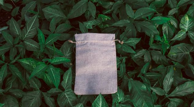 Blank Mockup Linen Cotton Tote Bag on Green Bush Trees Foliage Background. Eco Nature Friendly Style. Environmental Conservation Recycling Concept. Template for Artwork Text