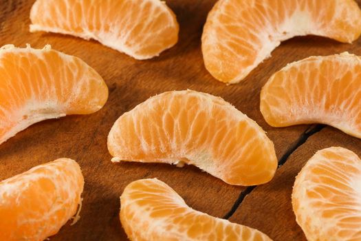 Fresh satsuma mandarin tangerine (Citrus unshiu) citrus fruit wedges on natural wood abstract, South Africa