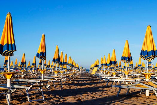 At the beach with sunbed  and blue-yellow beach umbrella in a bright day 