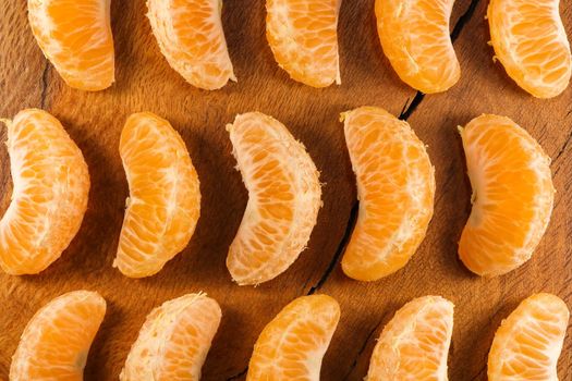 Fresh satsuma mandarin tangerine (Citrus unshiu) fruit wedge pattern layout on natural wood surface, South Africa