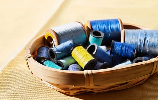 Spools of blue thread and one yellow spool in basket ,different size spools