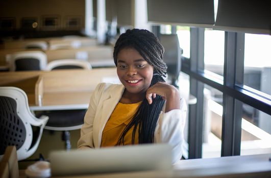 Young African American woman working using computer laptop concentrated and smiling.