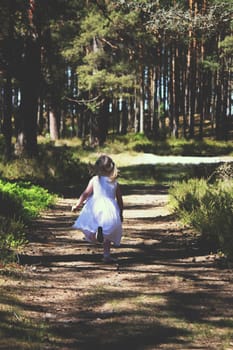 Little girl running in sunlight in the autumn park