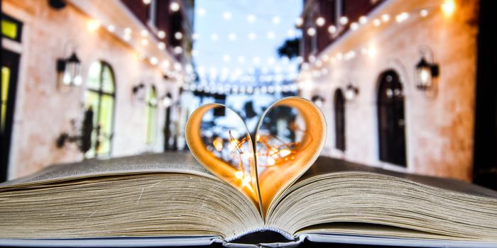 Book with love symbol isolated on cafe street background, Love books, love to read, love stories, heart shape from paper book, Romantic background with the book