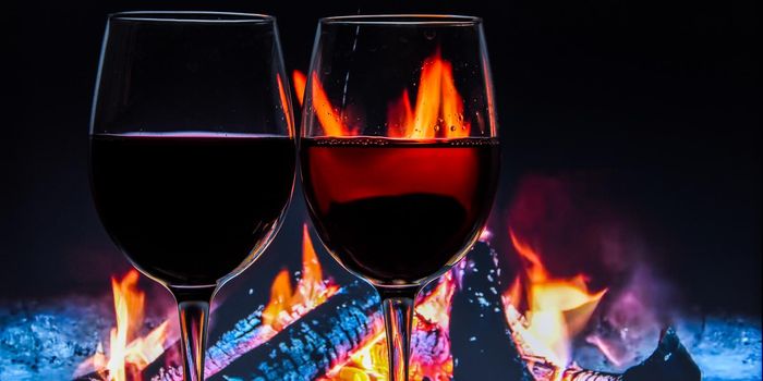 A glass of wine against the background of a burning fire. The atmosphere of rest and relaxation. Water drops, banner, christmas holiday, winter