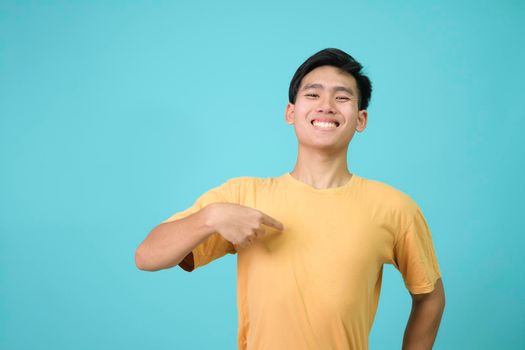 Young man looking confident with smile on face, pointing oneself with fingers proud and happy.