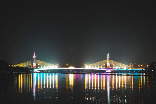 view of night scenery of city in Thailand  with beautiful reflections of skyscrapers and bridges by riverside in twilight. Cityscape view of bridge crosses the Chao Phraya River