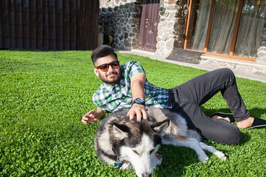 Young man sitting at green lawn and enjoying with his dog
