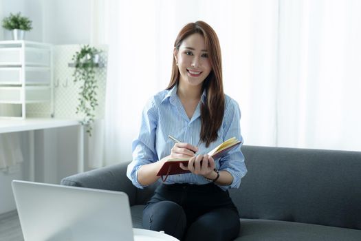 Portrait of a young businesswoman or business owner working with a notebook and computer at home.