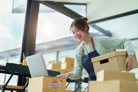 A portrait of a small startup, an SME owner, an Asian female entrepreneur checking orders to arrange the produce before packing the products in the inner boxes with the customers. Freelance concepts.