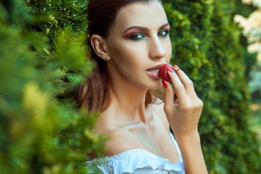 Closeup portrait of young adult woman with pretty face and sexy mouth with lips eating red sweet strawberry