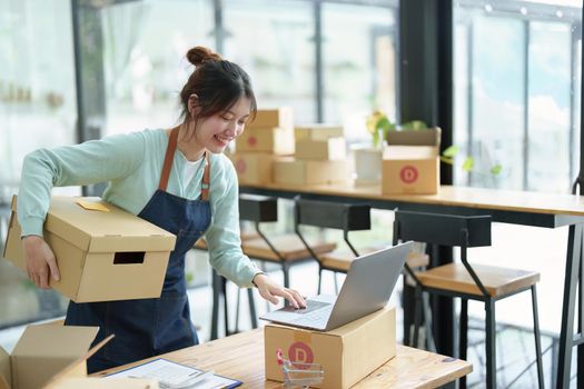 A portrait of a small startup, an SME owner, an Asian female entrepreneur checking orders to arrange the produce before packing the products in the inner boxes with the customers. Freelance concepts.