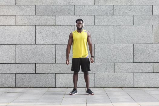 Perfect muscular big body. Body builder standing near gray wall. Copy space for text message or content