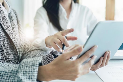 young Asian businesswoman using tablet computers to plan marketing strategies and invest to profit from customers.