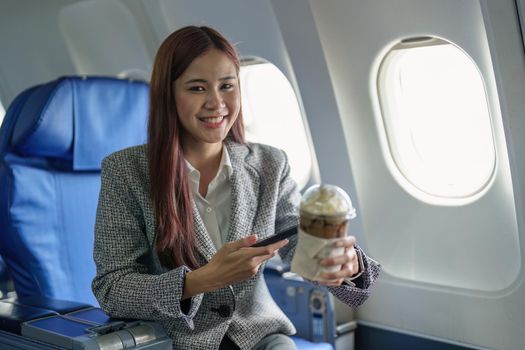 Portrait of a young Asian businesswoman smiling while riding a plane.