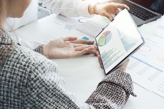 young Asian businesswoman using tablet computers to plan marketing strategies and invest to profit from customers.