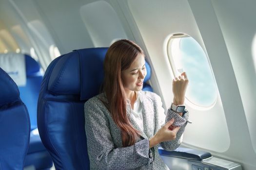 Portrait of a young Asian businesswoman smiling while riding a plane.