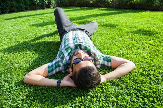 young man lie down on lawn and enjoying summertime.