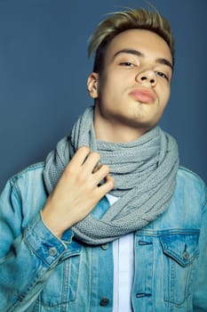 portrait of multiracial handsome man wearing jeans jacket and white shirt on blue wall background.